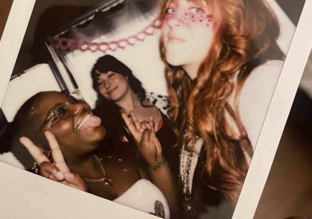 Three friends posing for a polaroid photo at a party